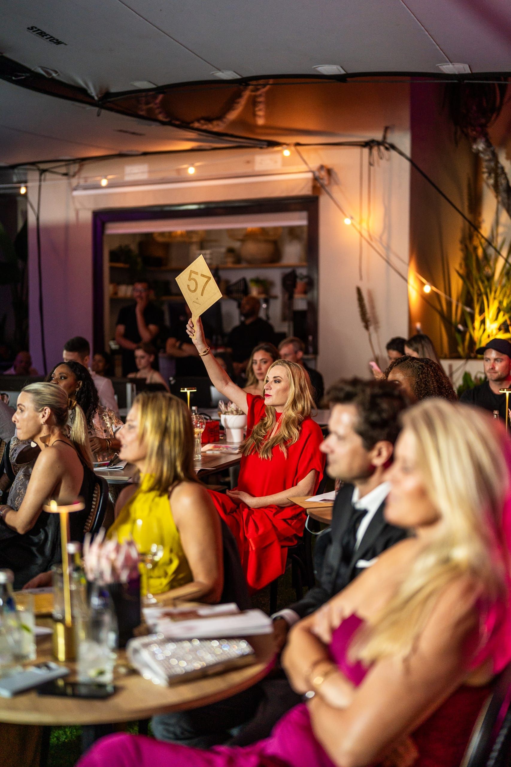 A guest raising a numbered paddle at the Art Angels charity auction