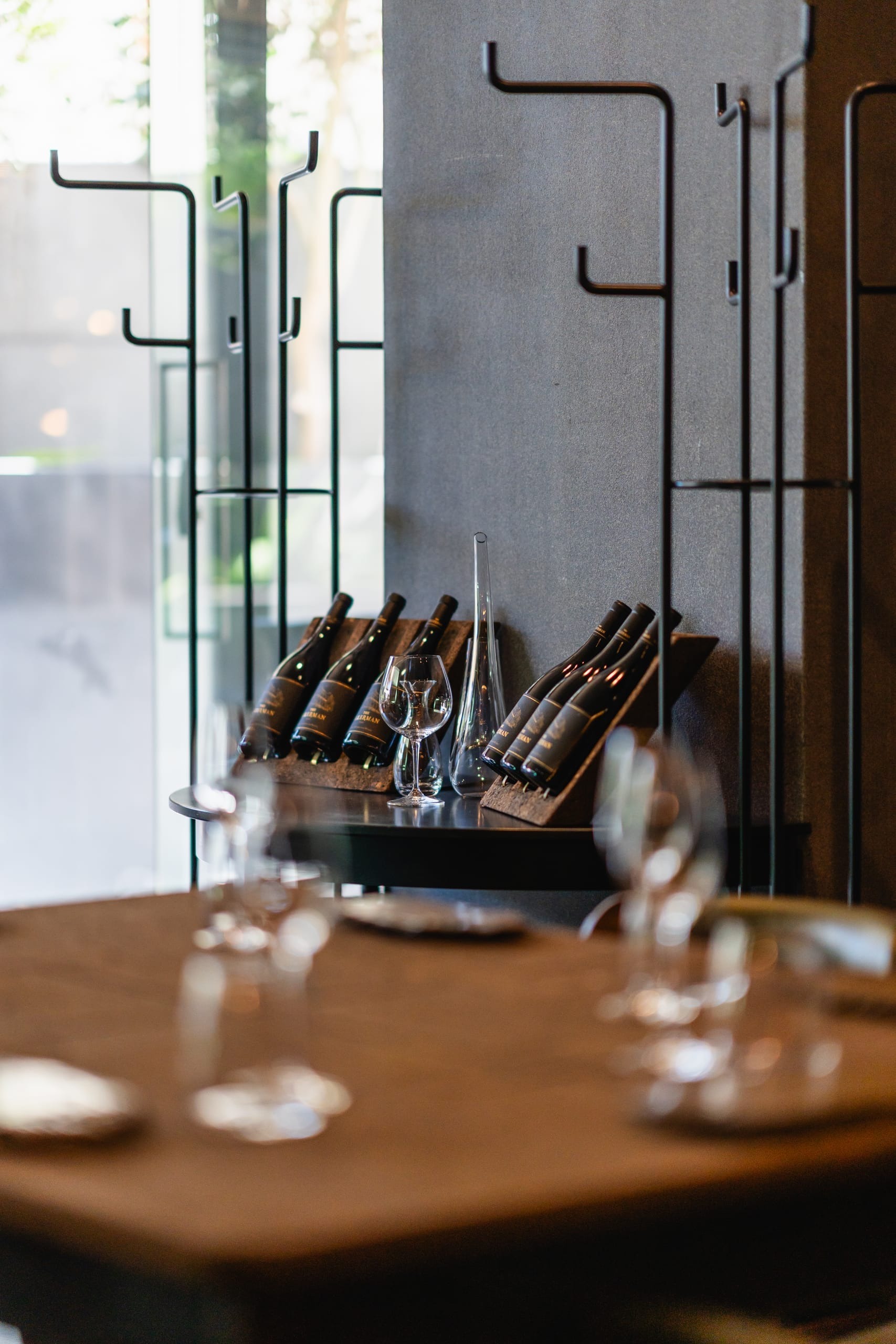 Bottles resting on a rack beside a set tasting table