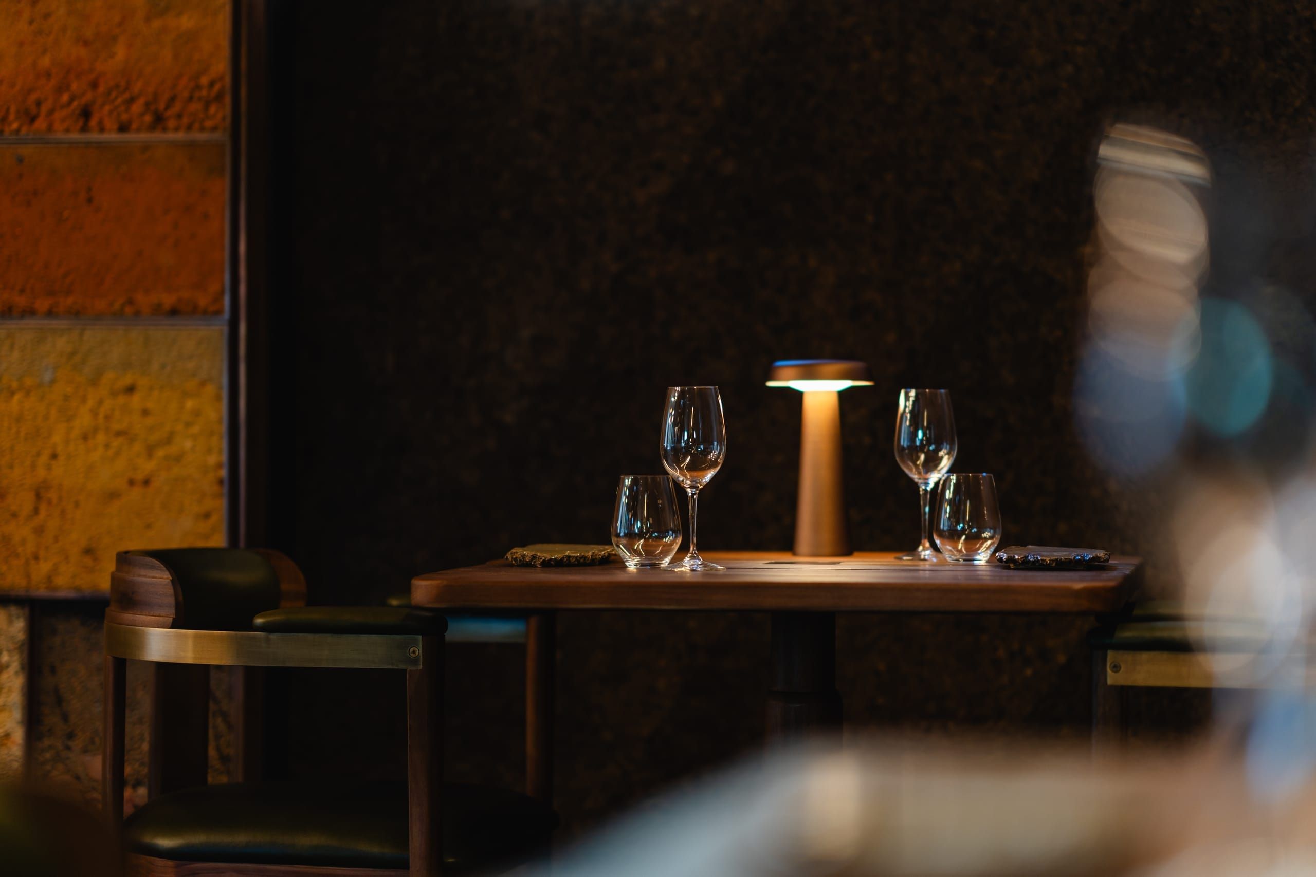 A candle-lit table set with glasses and a soft lamp at Ellerman House