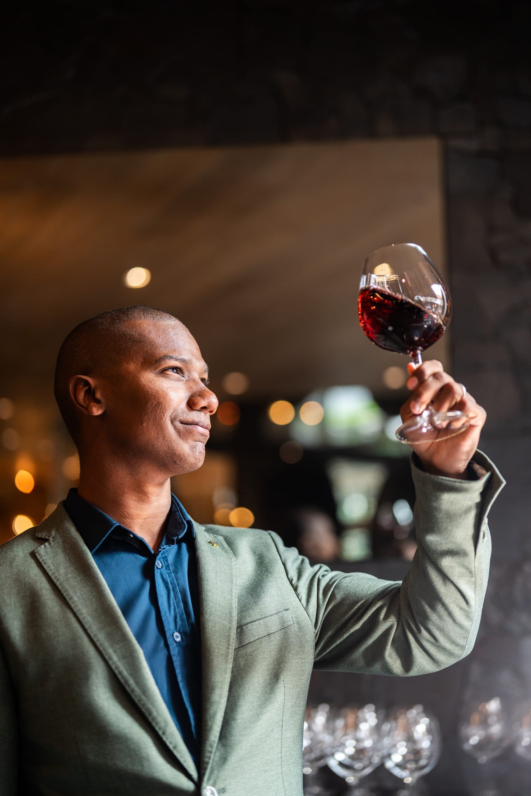 A guest holding a glass of red wine up to the light