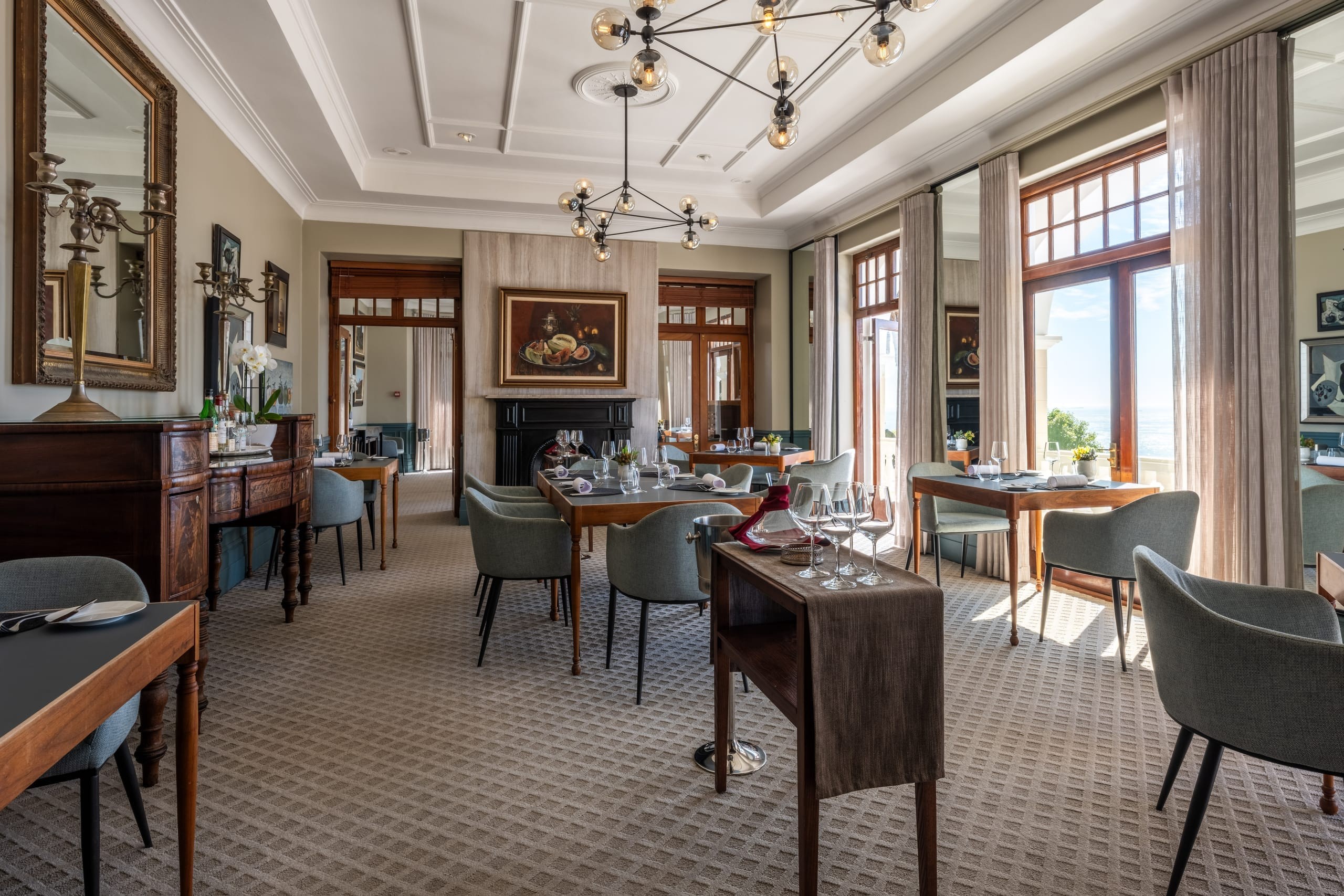 The OneEighty dining room with chandelier, fireplace and tables set among the art collection