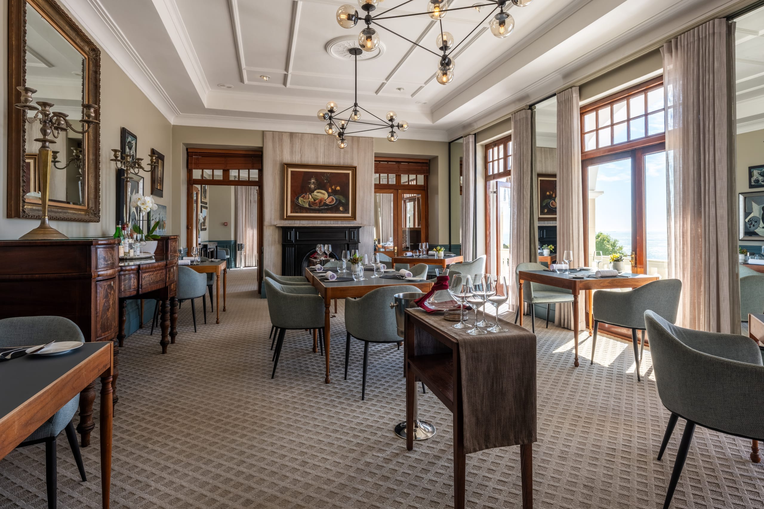 The OneEighty dining room with chandelier, fireplace and tables set among the art collection