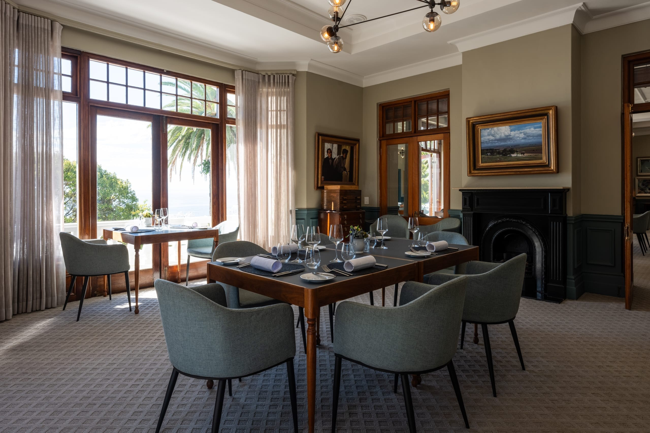 A private dining room with ocean light, original art, a fireplace and a set table