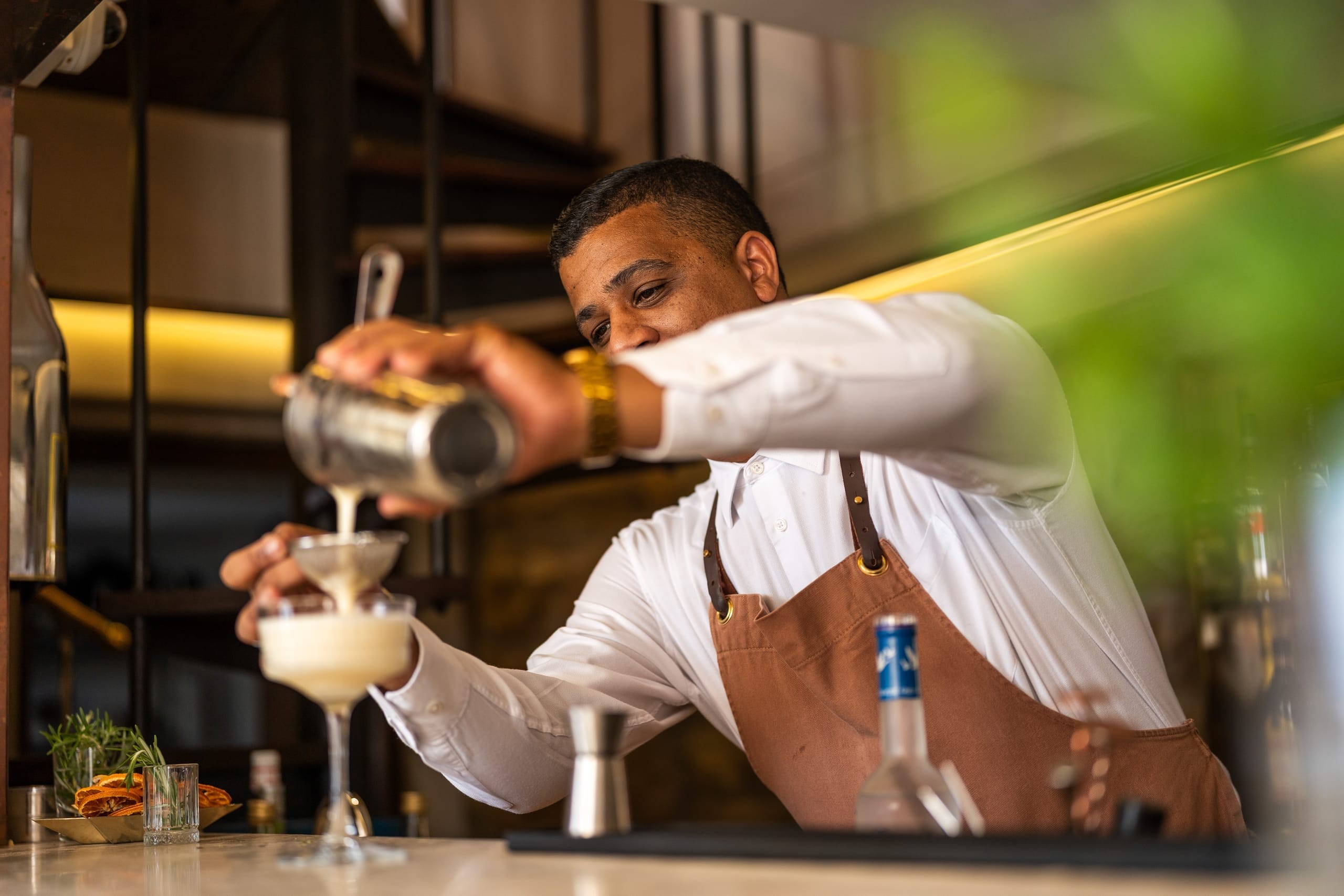 A bartender pouring a cocktail behind the bar at Bar Roc