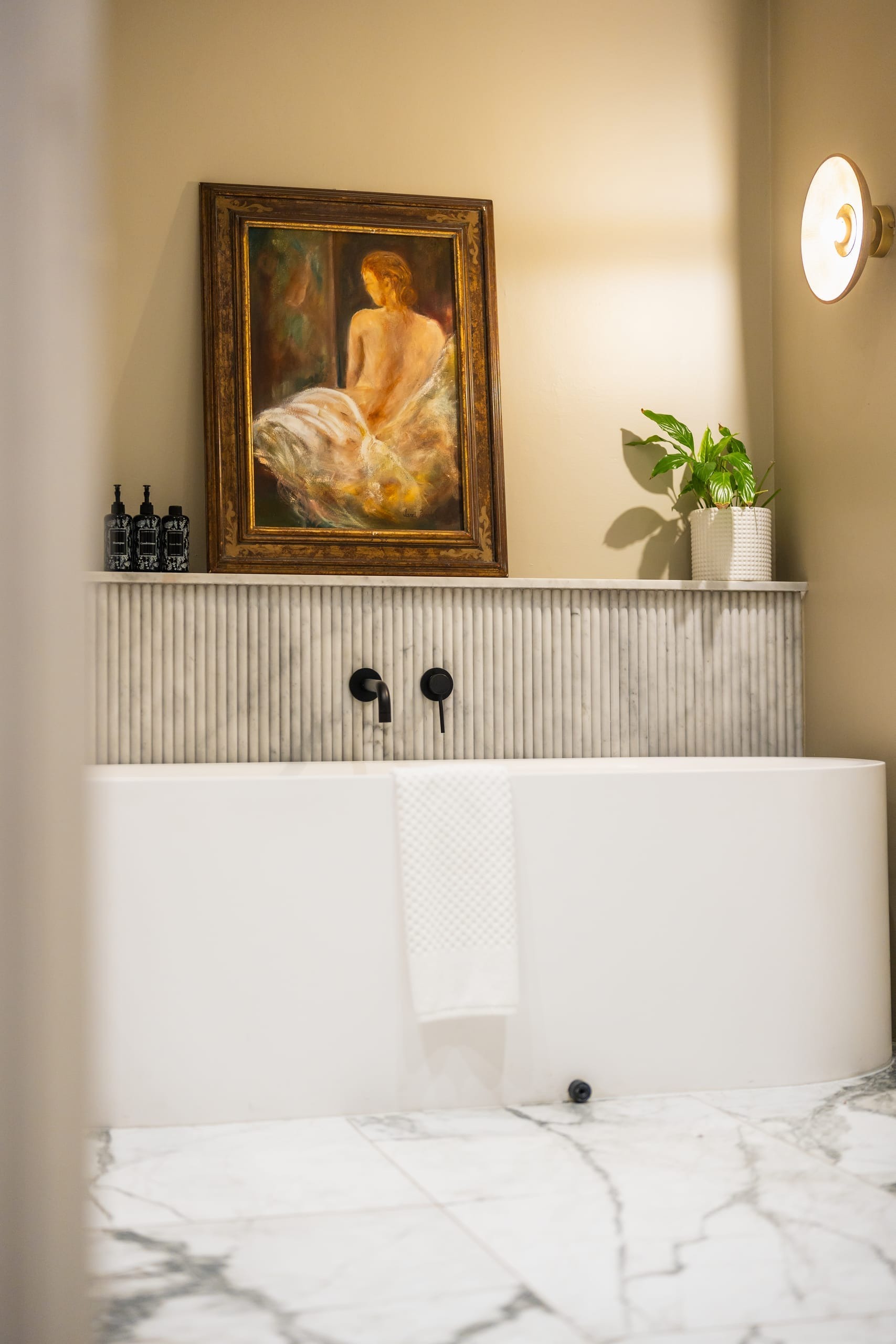 A framed figure painting above a marble bath