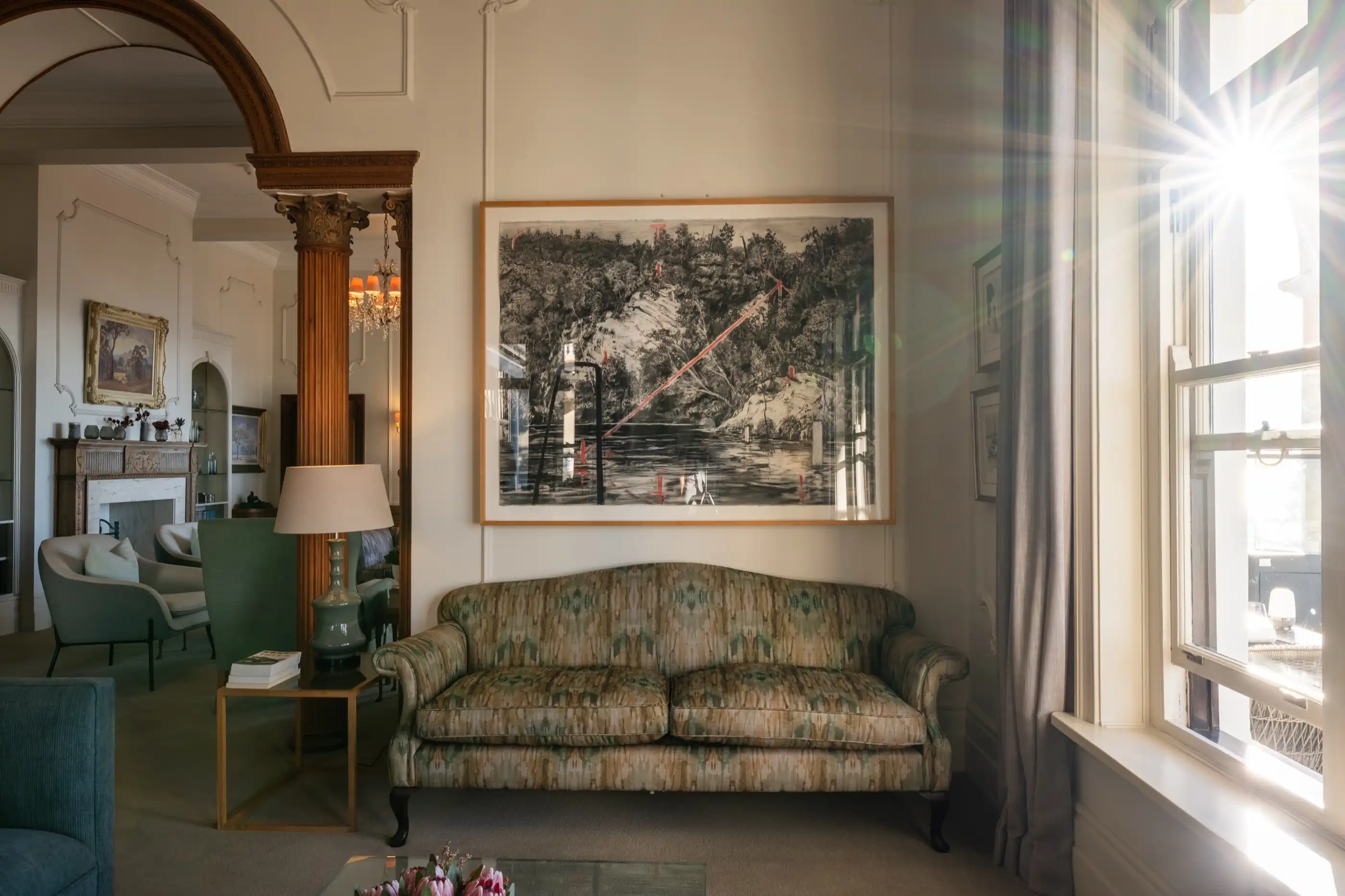 A sunlit period lounge with antique furniture and original artwork
