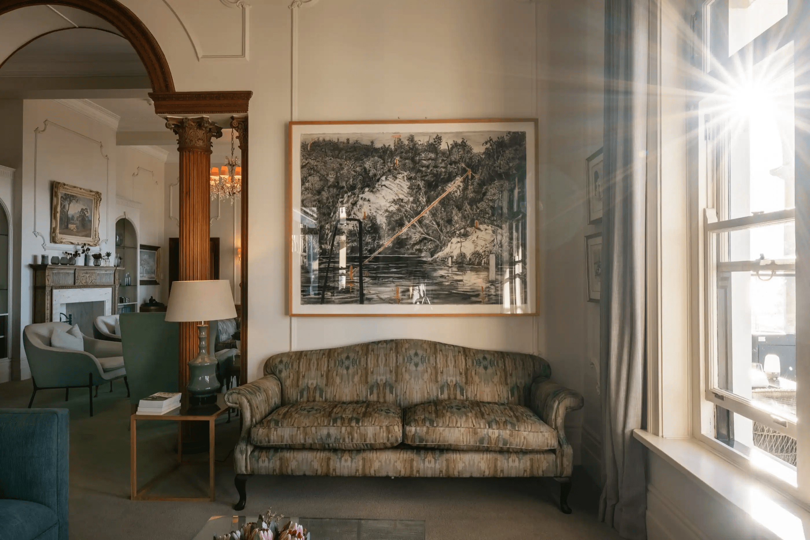 A sunlit period lounge with antique furniture and original artwork