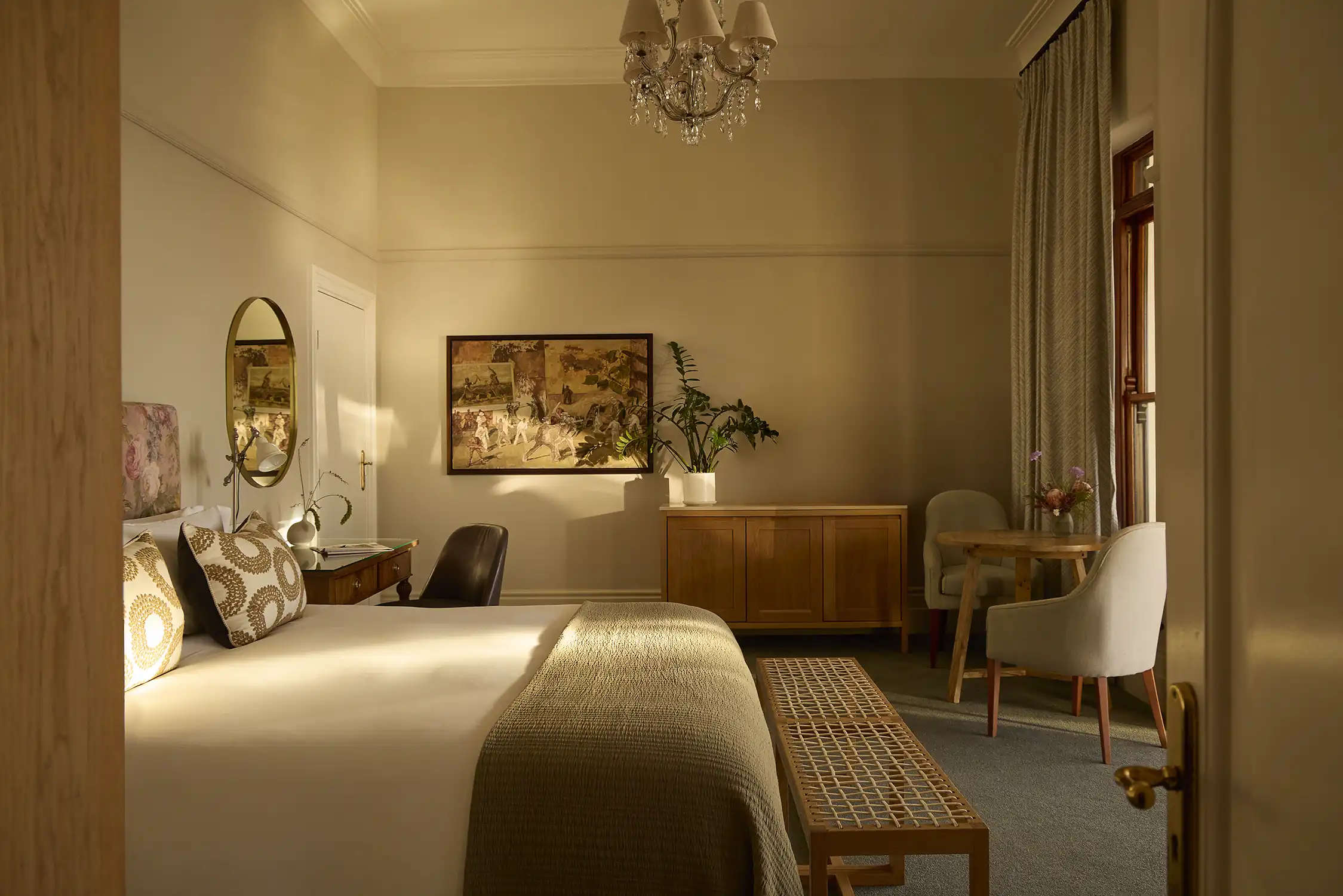 An elegant suite bedroom with soft light and layered linens