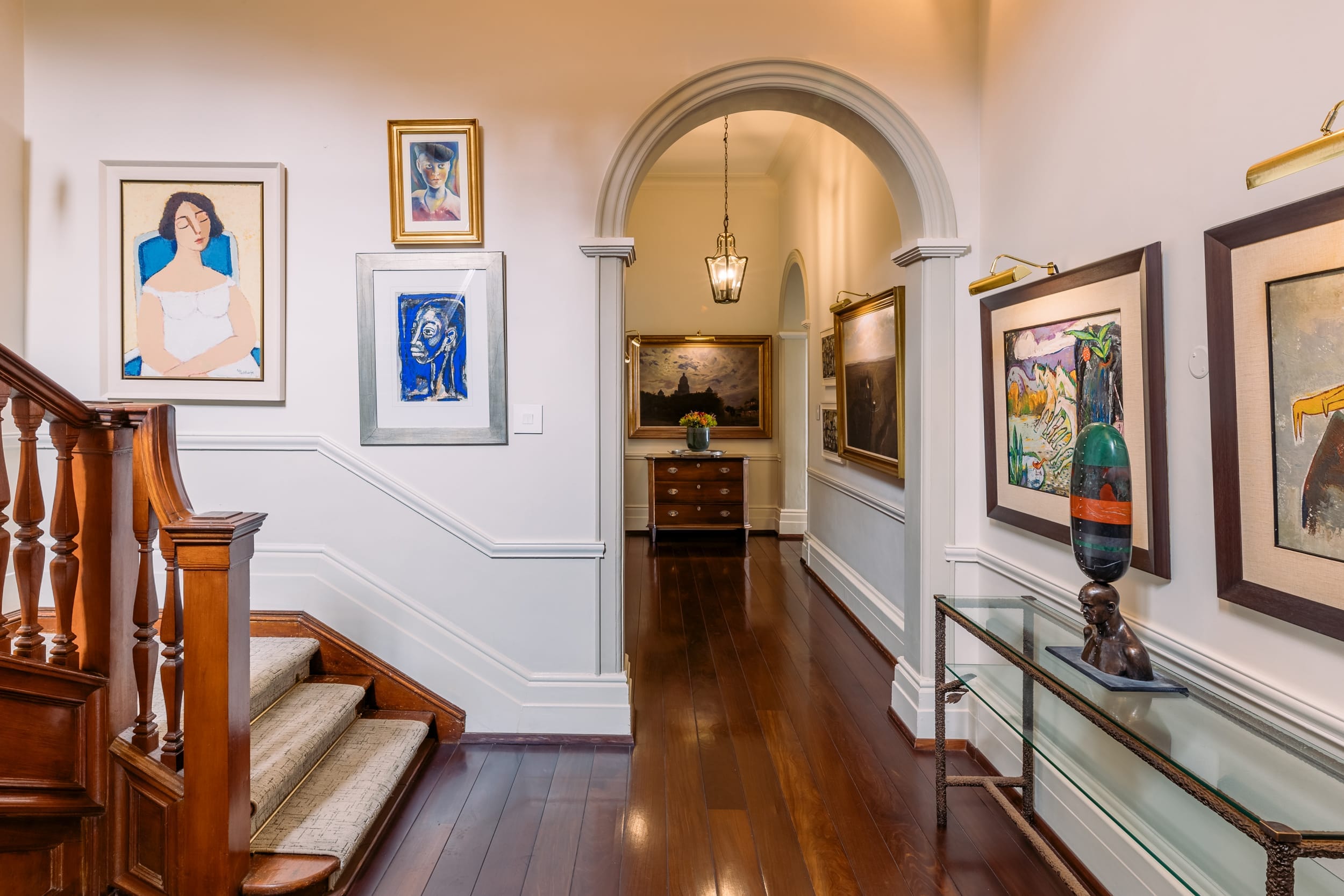 An arched passage hung with South African paintings and a bronze sculpture