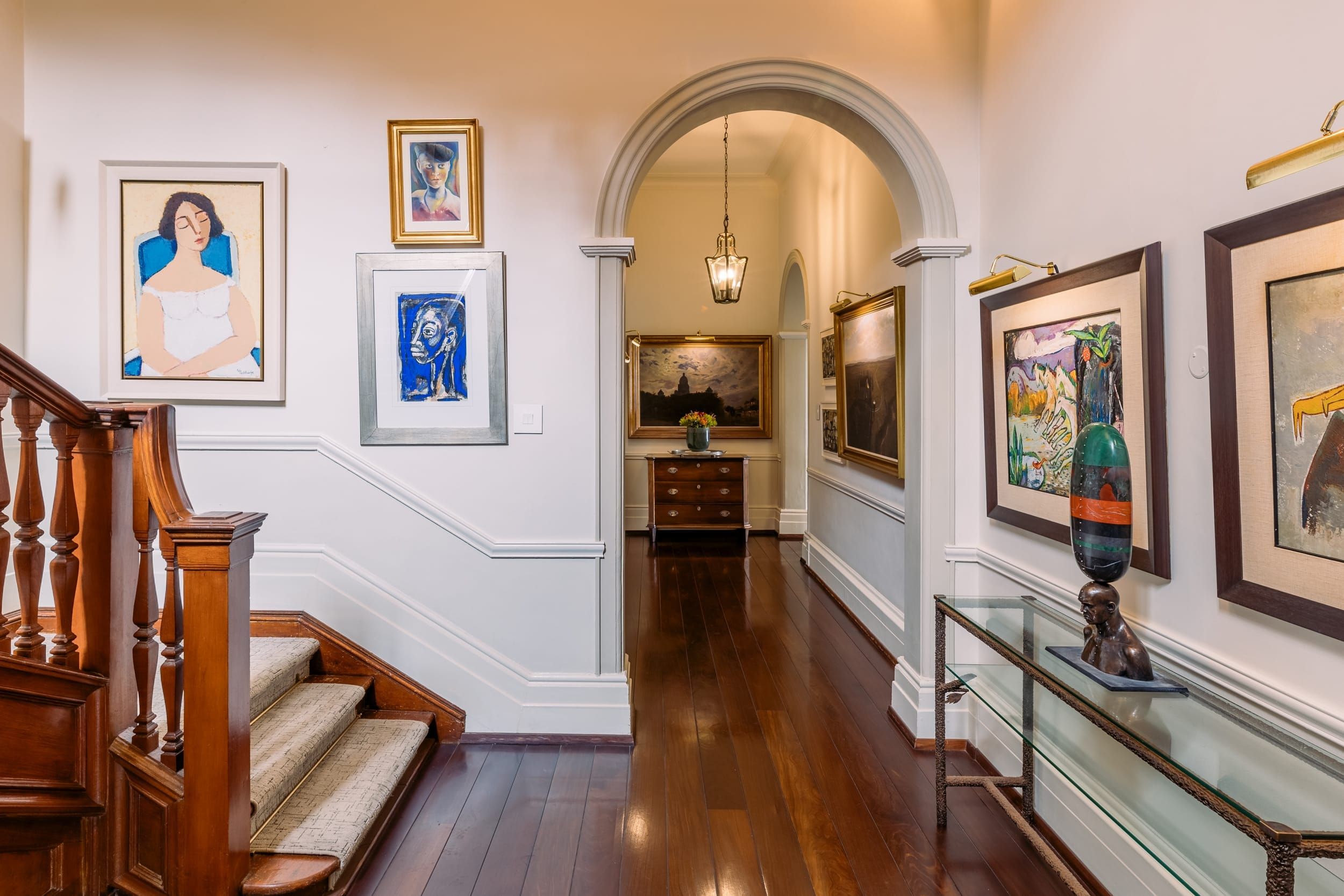 An arched passage hung with South African paintings and a bronze sculpture