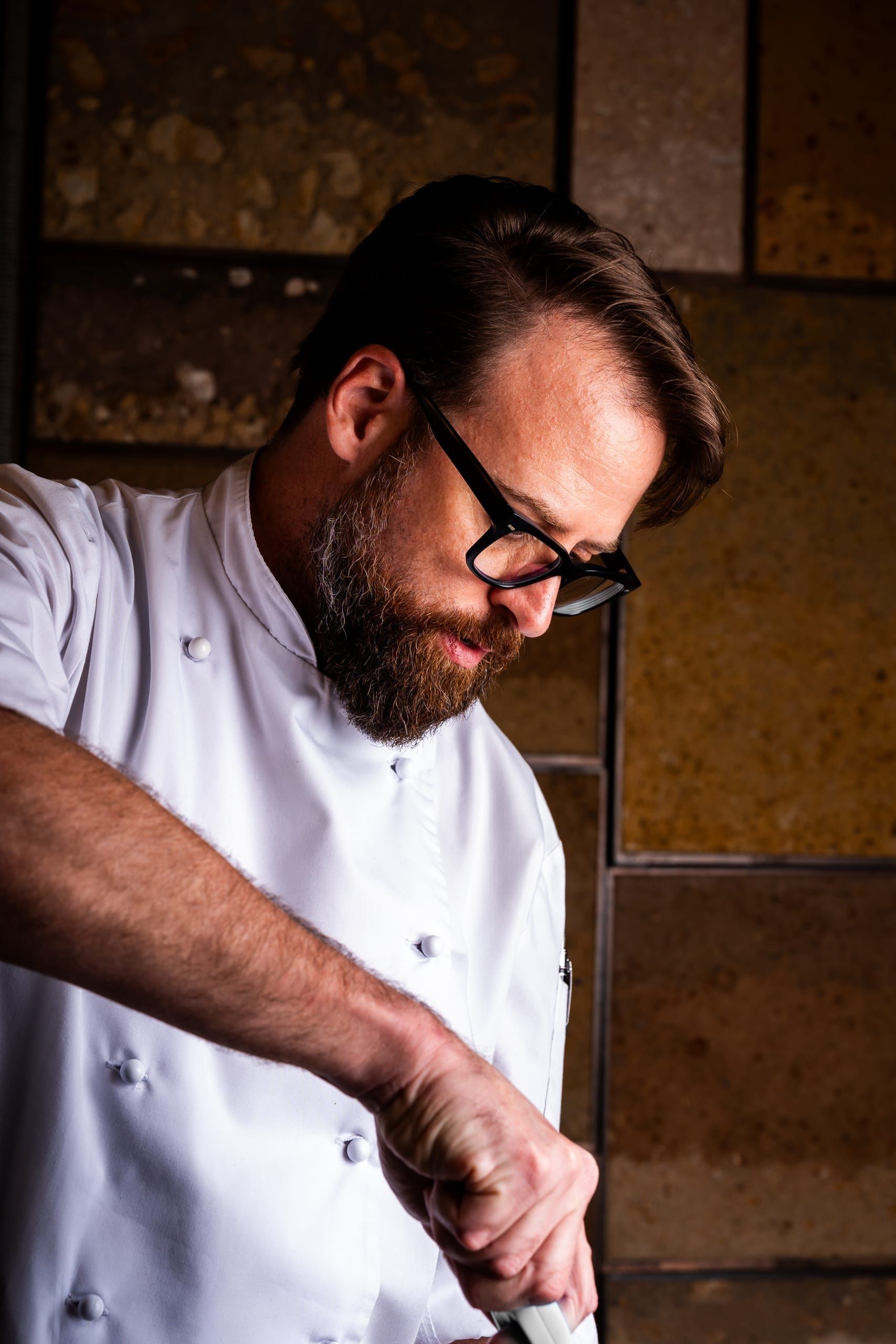 A chef plating a course in the kitchen at Ellerman House