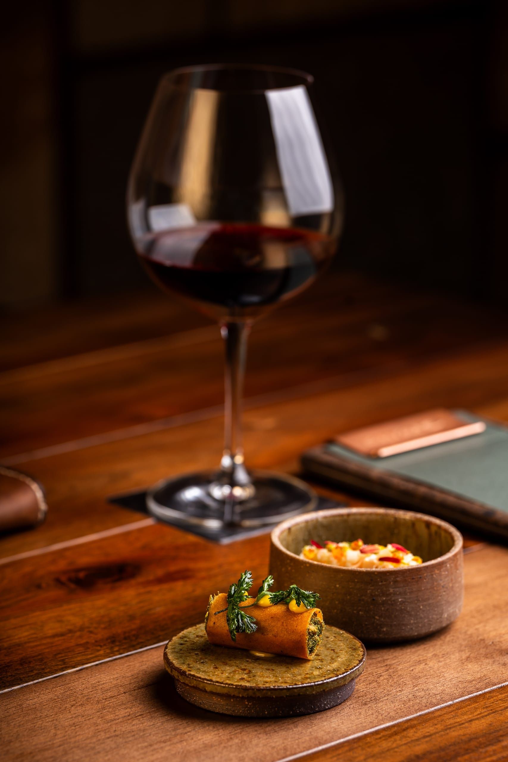 A delicately plated seasonal dish beside a glass of red wine