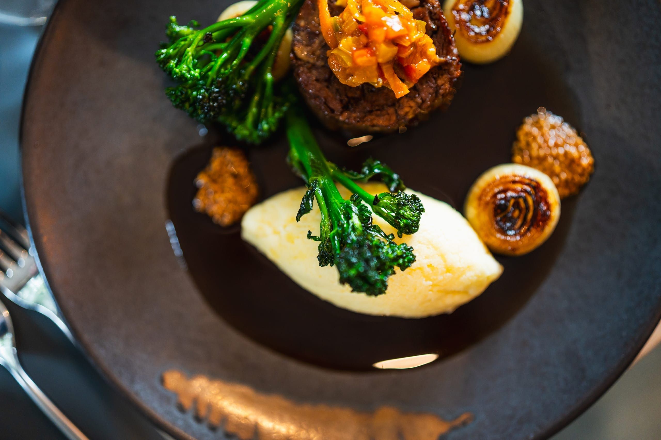 A seasonal main course of beef, broccolini and mash, viewed from above