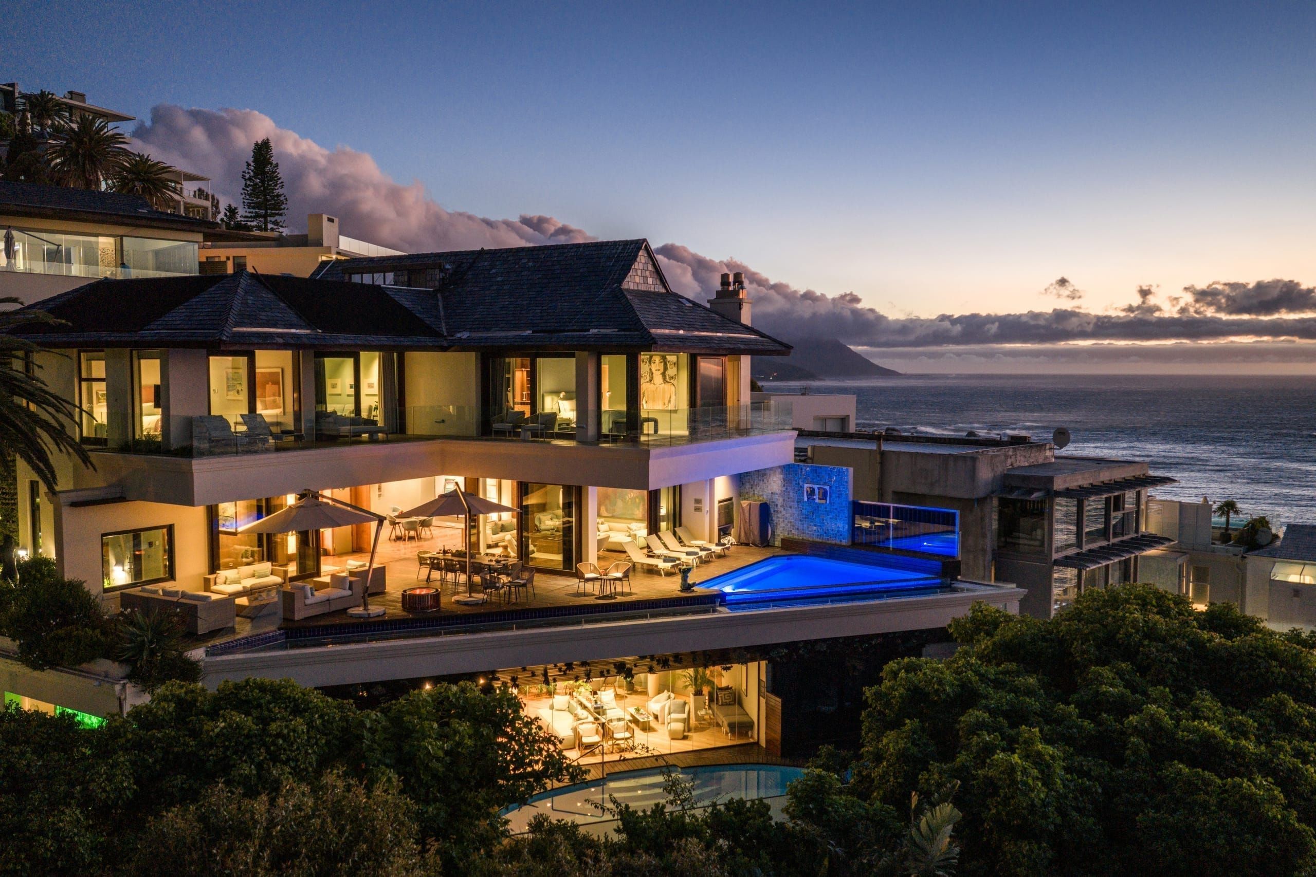 Illuminated villa with infinity pool above Bantry Bay at twilight