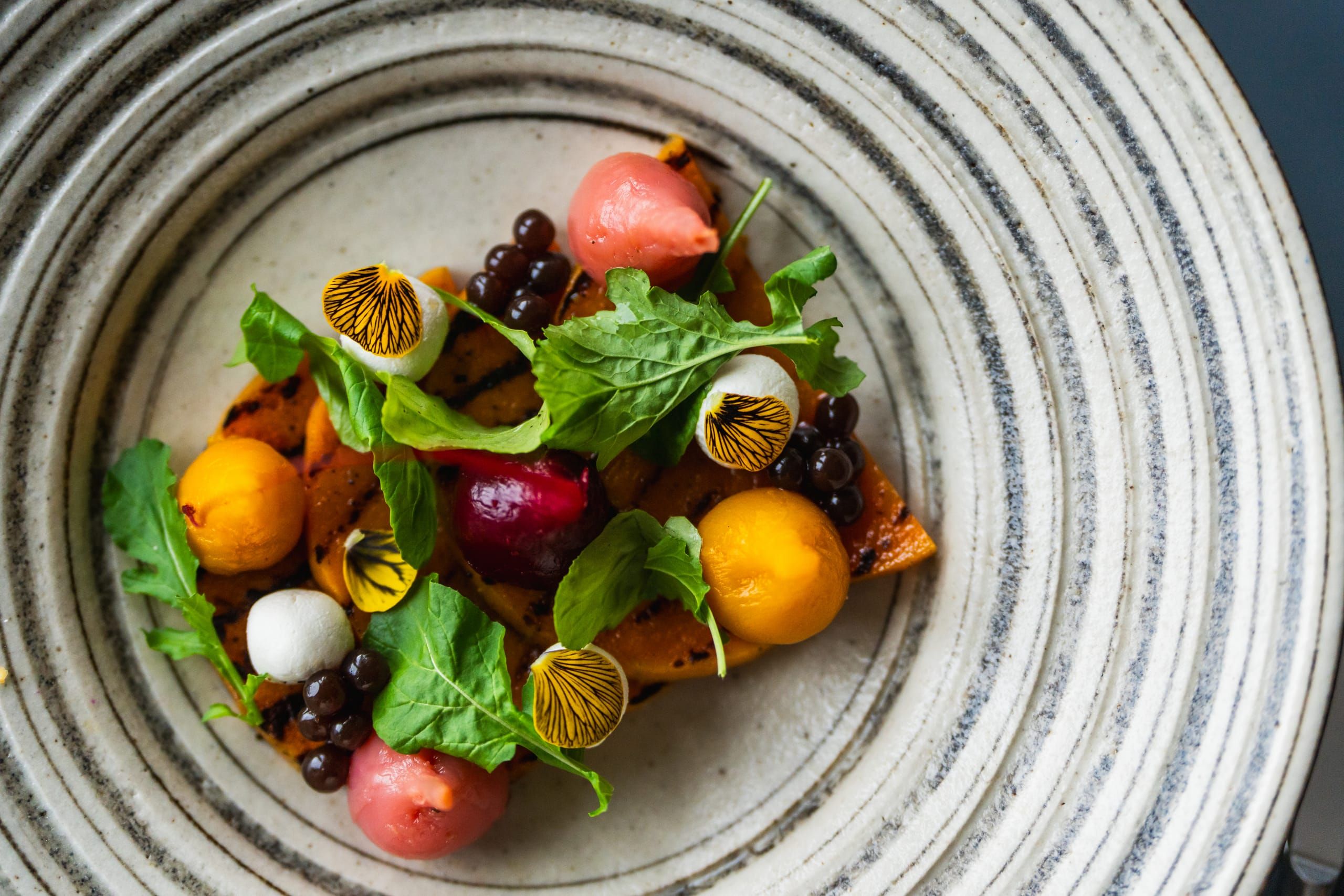 A delicate fish course with bok choy and tomatoes, viewed from above at OneEighty