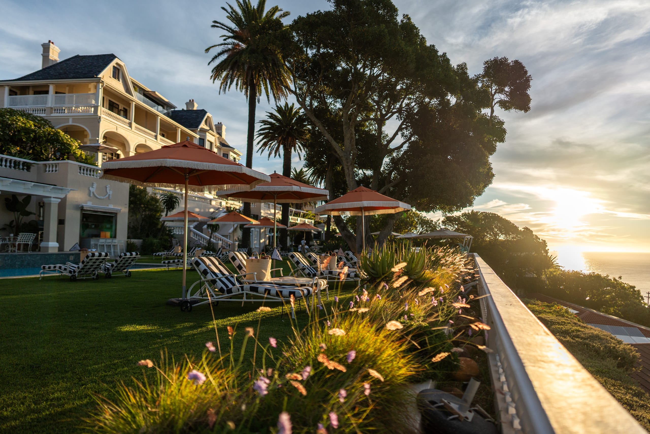 The lawn with orange umbrellas and loungers in golden afternoon light